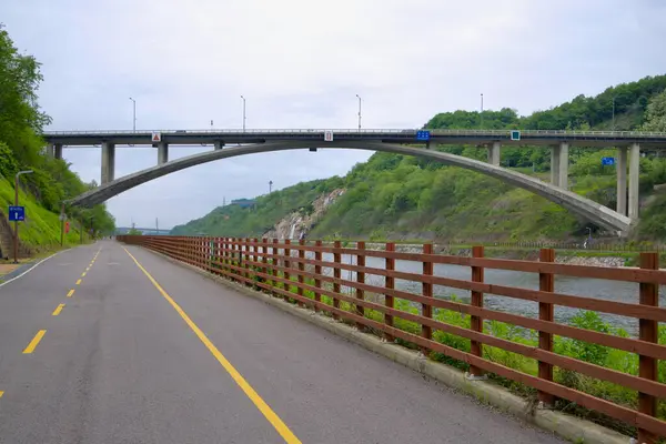 Incheon, Güney Kore - 19 Mayıs 2025: Moksang Köprüsü, Ara Bisiklet Yolu 'nun altından geçen, güvenlik rayları, ilkbahar yaprakları ve kanalın aşağısındaki uzak köprülerle çevrelenen Gyeongin Ara Su Yolu boyunca uzanır..