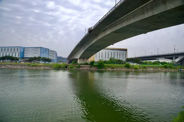 Incheon, Güney Kore - 19 Mayıs 2025: Hana Köprüsü 'nün beton açıklığı Ara Hangang Lock yakınlarındaki Ara Waterway üzerinde, sanayi depoları ve aşağıdaki sakin kanal sularıyla kavis çiziyor.