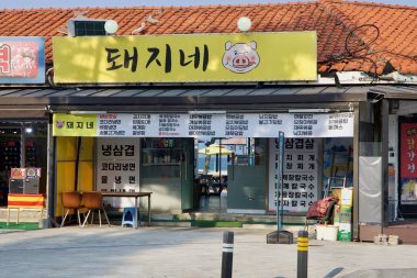 Donghae, Güney Kore - 1 Haziran 2025: Piknik masalarına ve Mangsang Sahili 'ne bakan şemsiyelere doğru parlak sarı işaretli sıradan bir domuz eti lokantası açılıyor ve lokantalara Doğu Denizi manzarası sunuluyor..