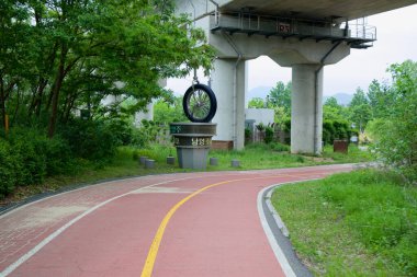 The Balgeun Gwangjang plaza and bike path wind beneath the Bukhangang Railroad Bridge, where cyclists rest, stamp passports.