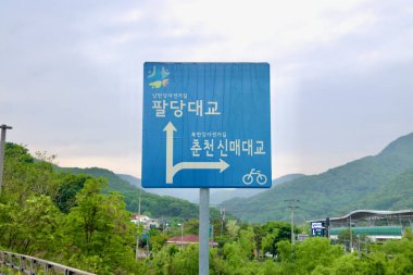 Namyangju City, South Korea - May 19th 2025: A blue directional sign marks the junction of the Namhangang and Bukhangang bike paths near Ungilsan Station, pointing riders toward Paldang Bridge and Chuncheon.