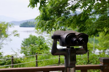 Namyangju, South Korea - May 19th 2025: A public binocular viewer overlooks the scenic riverside near Dumulmeori, where the North and South Han Rivers converge near Yangpyeong.