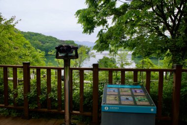 A mounted binocular viewer and bird observatory sign offer views toward Yangpyeongs Dumulmeori, where the North and South Han Rivers meet amid rich wetland habitat.
