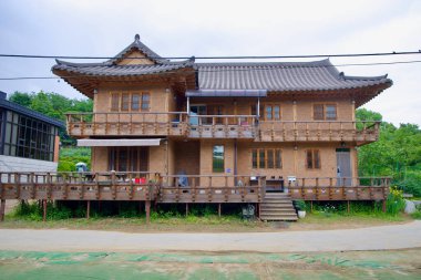 Namyangju, Güney Kore - 19 Mayıs 2025: Geleneksel Kore mimarisi ile ahşap parmaklıklar, kafes pencereleri ve yükseltilmiş bir güverte içeren iki katlı hanok esinlenilmiş bir ev.
