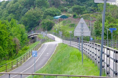Namyangju City, South Korea - May 19th 2025: A gentle ramp connects the Hangang Bike Path to the Bukhangang section, guiding cyclists through green hills and tree-lined corridors near Ungilsan.