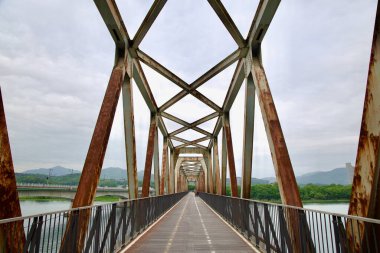 Yangpyeong County, South Korea - May 19th 2025: A closer view inside the Bukhangang Railroad Bridge shows crisscrossing steel trusses weathered by age, now framing a peaceful bike route above the river.