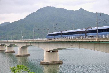 Bir GyeonguiJungang Hattı banliyö treni Yangsu Demiryolu Köprüsü 'nden süzülüyor. Pürüzsüz arabaları ormanlı dağ yamaçlarının altından Kuzey Han Nehri' ne doğru ilerliyor..
