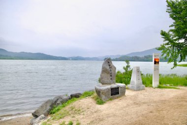 Yangpyeong County, South Korea - May 19th 2025: Stone monuments mark Dumulmeori, where the North and South Han Rivers meet, offering a quiet riverside view with distant mountains and cultural significance.