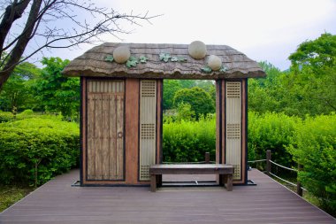 Yangpyeong İlçesi, Güney Kore - 19 Mayıs 2025: Ahşap dokular, kafes panelleri ve oyulmuş kavunların yer aldığı tuhaf geleneksel kapı Supul-ro Eco Park 'ta bir platform dekore ediyor.
