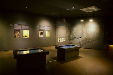 Gongju, Güney Kore - 13 Haziran 2025: Bekçe mezarlarıyla ilgili bir müze sergisinde Kore ve Japonya bölgelerinde defin geleneklerini vurgulayan interaktif dokunmatik ekranlar, duvar destekli diyagramlar ve eser kopyaları yer alıyor..