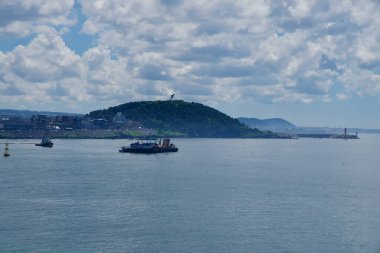 Bir vinç mavnası ve römorkör, Eoyeong Parkı 'nın karşısındaki yeşil bir burnun yanında dalgakıran ve şehir mahallelerini gösteren kırmızı bir deniz feneri işletiyor..