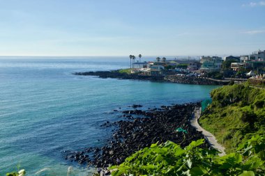 Handam Sahili ve Handam Sahil Yolu 'nun üstündeki kayalıklardan turkuaz su siyah bazalt ve kıyı şeridi boyunca kafelerin kümelendiği köye doğru palmiye ağaçlarının arasından geçen bir sahil yolu turkuaz turu yapar..