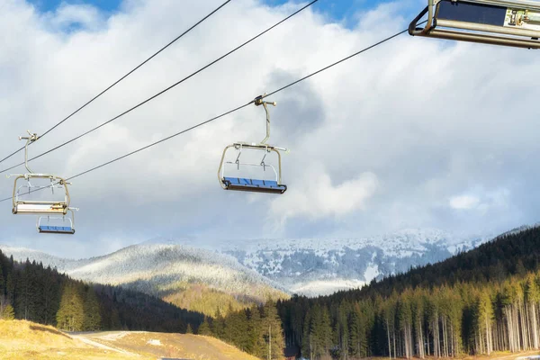 Kar kaplı dağların arka planında kayak kaldırma
