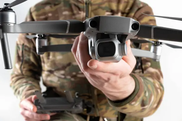 Concept of using drones in modern warfare. Close-up of a drone in hands of a soldier on white background. Military use of drones
