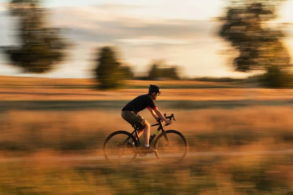 Rowerzysta Żwirowym Rowerze Polu Zachodzie Słońca Efekt Rozmycia Ruchu Koncepcja — Zdjęcie stockowe