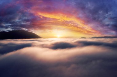 Gün doğumunda, alçak yoğunluklu sis içindeki dağlar. Siste dağ zirveleri olan güzel bir manzara. Bulutlardaki dağ vadisi.