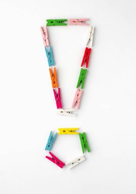 Beyaz arka planda renkli ahşap mandallardan ünlem işareti. Üst görünüm.