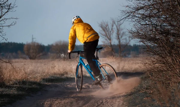 Cyclist on a gravel bike rides along the trail raising dust from the rear wheel. Gravel biking. Extreme sports and active lifestyle concept.