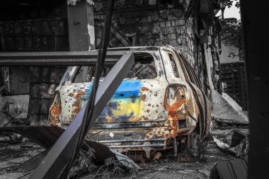 Bagajında Ukrayna bayrağı olan yanmış bir araba havan topu atışından dolayı harap olmuş bir evin bahçesine park edilmiş. Irpin, Kyiv bölgesi, 2022. Ukrayna 'da Savaş.