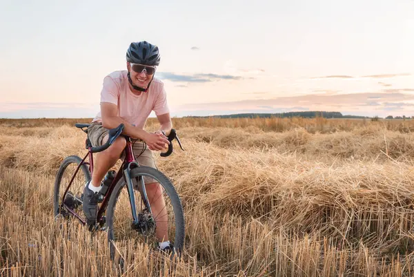 Rowerzysta Stoi Polu Zachodzie Słońca Piękny Krajobraz Człowiekiem Kasku Okularach — Zdjęcie stockowe