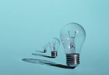 Pastel mavi arka planda üç ampul. İlham ve yaratıcılık kavramı.