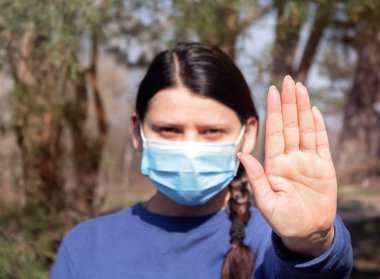 Tıbbi maske takan kız avuç içi gösteriyor. Virüs Hastalıkları Konseptini durdur. Tehlikeli ölümcül NCoV salgını.