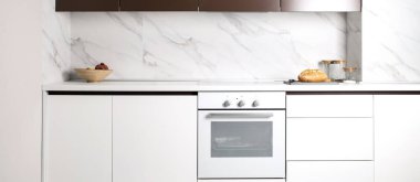 Beyaz mutfak iç kısmı. Tezgahın üstünde bir somun ekmek yatıyor. Minimalizm