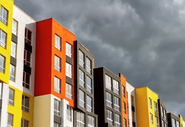 Colored facade of a modern building against a stormy sky.