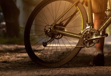 Arka farında bisikleti olan adam. Yumuşak güneş ışığında çakıllı bir bisikletin arkasında.
