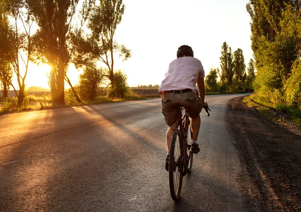 Mężczyzna Rowerze Zachodzie Słońca Jeździ Pustą Asfaltową Drogą Koncepcja Aktywnego — Zdjęcie stockowe