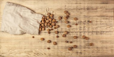 Büyük bir çuval dolusu ceviz ve fındık. Fındıklar büyük bir tahta üzerine saçılmış. Ahşap arka plan. Üst görünüm.