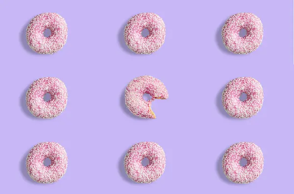 Collage of pink doughnuts in glaze on a pink background. Lots of donuts mosaic, a tasty fresh pink donut drizzled with glaze. One donut in the center bitten