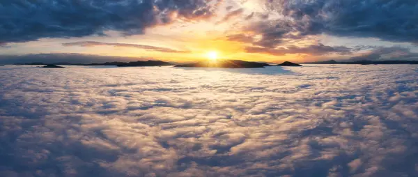 Beautiful sunset sky above the clouds with silhouettes of mountain peaks with dramatic light. Aerial drine view.