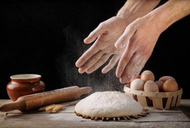 Adam ahşap mutfak masasında ekmek hamuru hazırlıyor. Ev yapımı ekmek yapmak..
