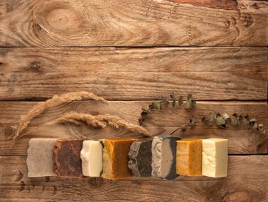 Ahşap arka planda farklı el yapımı sabun kalıpları. Mesaj için yer var. Organik kozmetik konsepti.