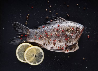 Crucian sazanı siyah arka planda biber, tuz ve limonla pişirmeye hazır..