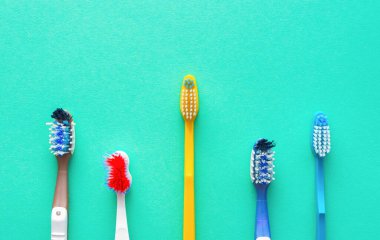 Turkuaz arka planda farklı diş fırçaları. Sağlık hizmeti kavramı.