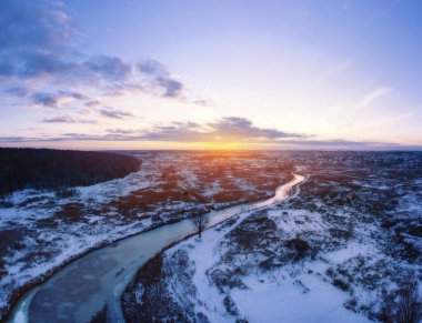 Kış manzarası, donuk nehirle kaplı, karla kaplı, güzel günbatımı gökyüzü. Manzaralı hava görüntüsü.