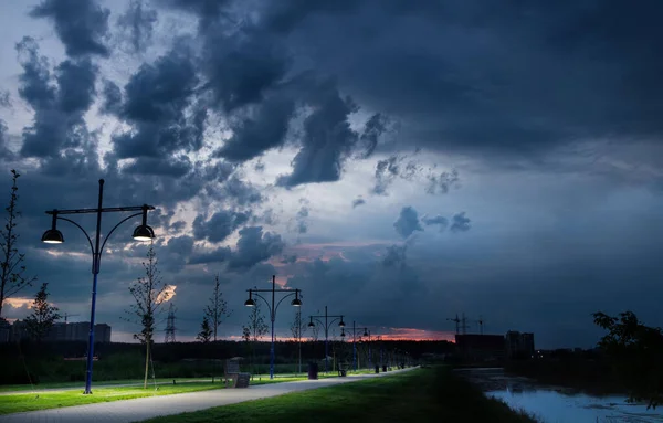 Şehir Parkının Nehir Kıyısındaki Yolu Gökyüzünde Yağmur Bulutları Fenerler Var — Stok fotoğraf