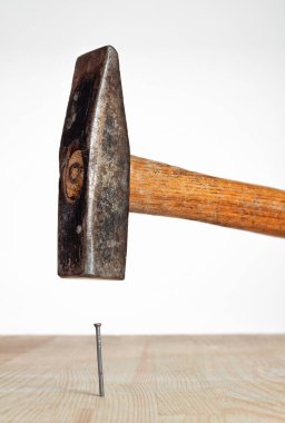 Çekiç çivisi beyaz zemin üzerinde tahta bir kalasa çarptı..