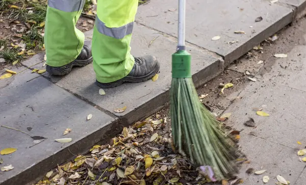 belediye işçisi süpürge sapı ile yol süpürme ve kepçe çöp toplar. sanitasyon işçi süpürme sokak
