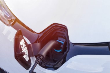 Şarj istasyonundaki elektrik kablosu takılı elektrikli araba. Alternatif enerji kullanımı. Yükleme işlemi.