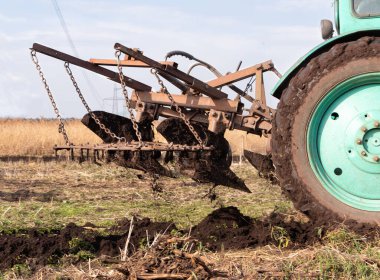 Traktör tarlayı sürüyor, yaklaşın. Baharda tarlada tarım işi. Yan görünüm.