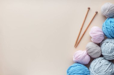 Pastel arka planda yumuşak ipliğin yanında ahşap örgü iğneleri var..