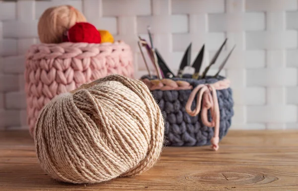 Closeup of knitting yarn with knitted baskets on wooden table. Concept of handmade.