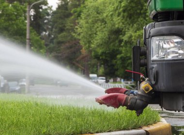 Sokaklardaki çimleri sulayan belediye kamyonunun yakın çekimi..