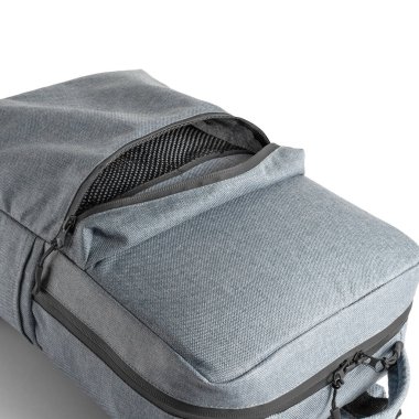 Beyaz zemin üzerinde çeşitli ögeler için açık ek bir cep içeren mavi bir sırt çantasının üst görünümü.