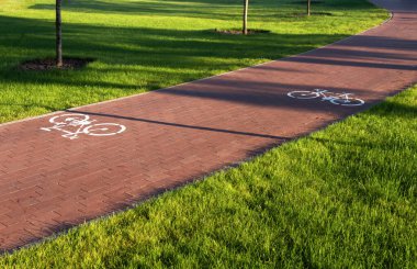 Şehir parkındaki yol üzerinde yeşil çimenli bisiklet işaretleri olan bisiklet yolu. Güvenli bisiklet konsepti.