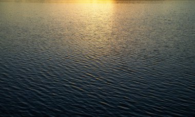 Batan güneşin altında dalgalarla su yüzeyi.