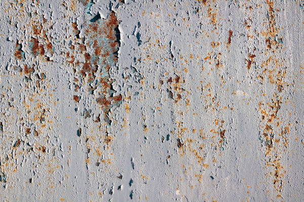 Peeling paint on a rusty metal surface.